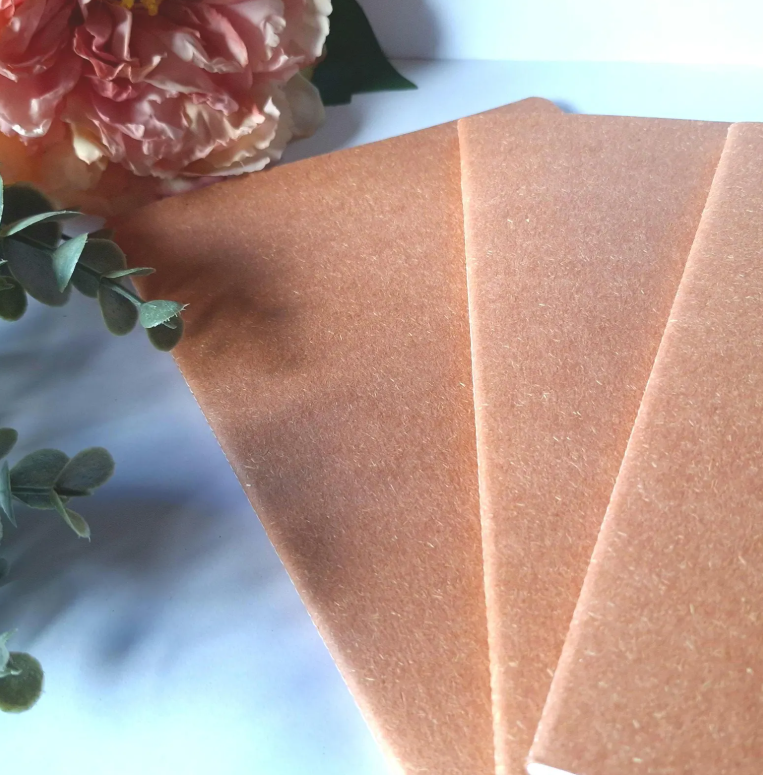 Close-up of a pink flower and textured earthy pink paper on a light background
